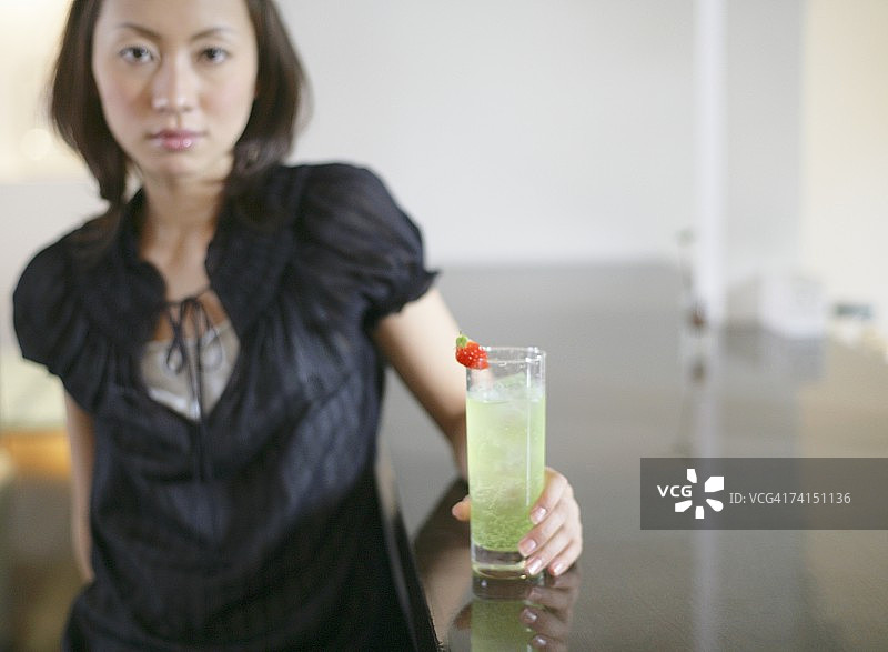 日本女人看着镜头，手里拿着一杯鸡尾酒图片素材