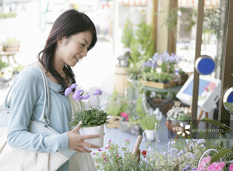 在花店面带微笑赏花的日本女人图片素材