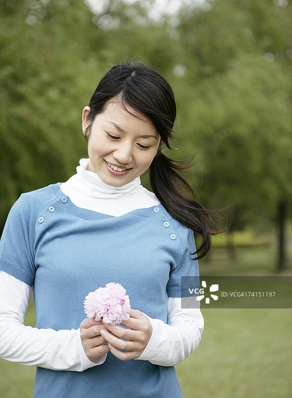 手持鲜花在公园里微笑的日本女人图片素材