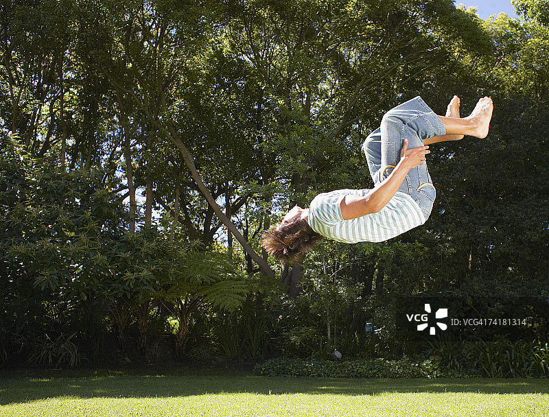 在户外树林中后空翻的青少年男孩图片素材