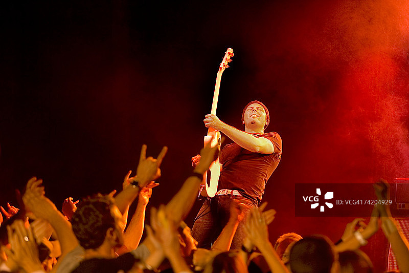 摇滚吉他手在舞台上为观众表演（低角度）图片素材
