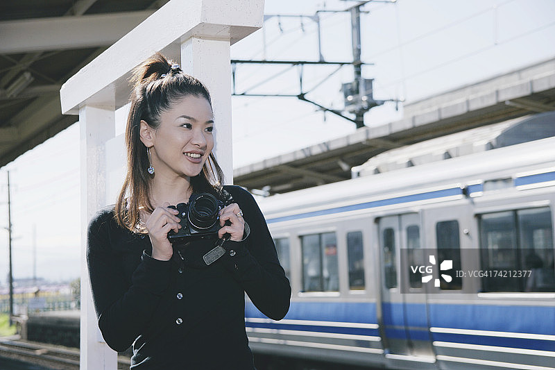 年轻女子在火车站台上拍照图片素材