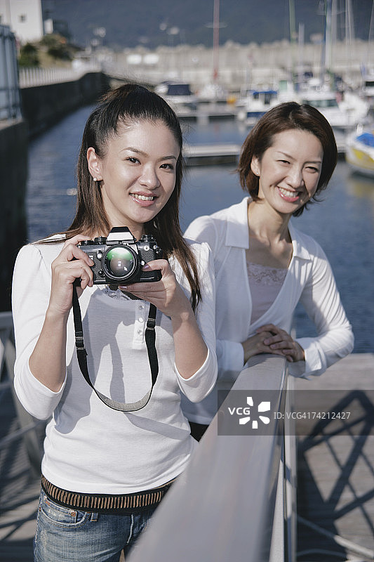 两名年轻女子在码头，一个拿着相机图片素材