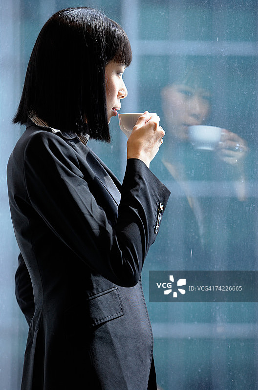 商务女人靠窗站立喝咖啡（上半身）图片素材