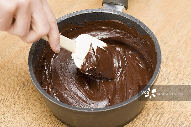 用刮刀在平底锅中搅拌融化的巧克力图片素材