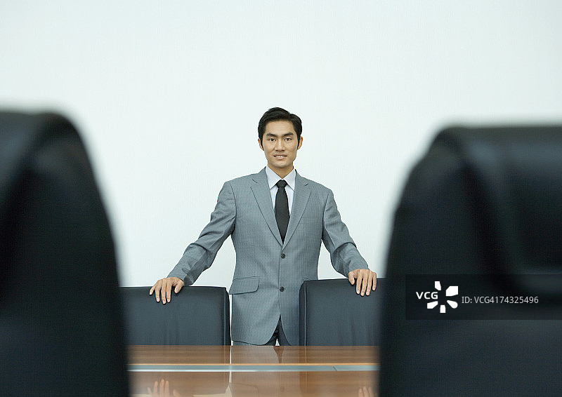 站在会议室，手扶椅背的商人肖像图片素材