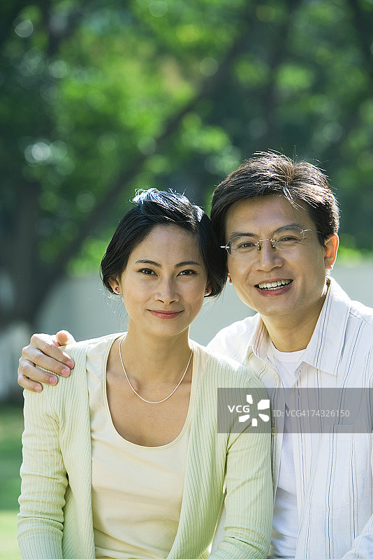 情侣对着镜头微笑，男人搂着女人图片素材