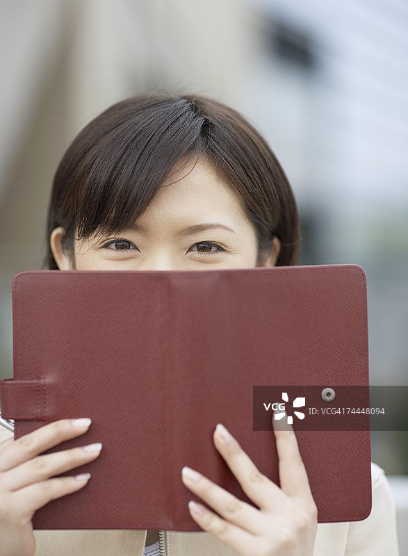 用日程本遮住脸的日本女商人图片素材