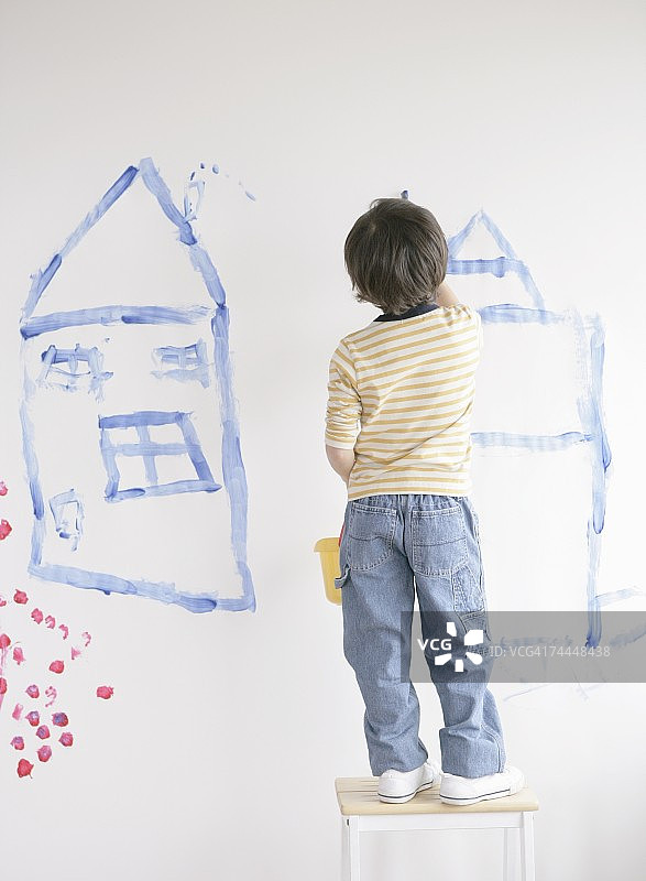 加拿大男孩在房间的墙上画画图片素材