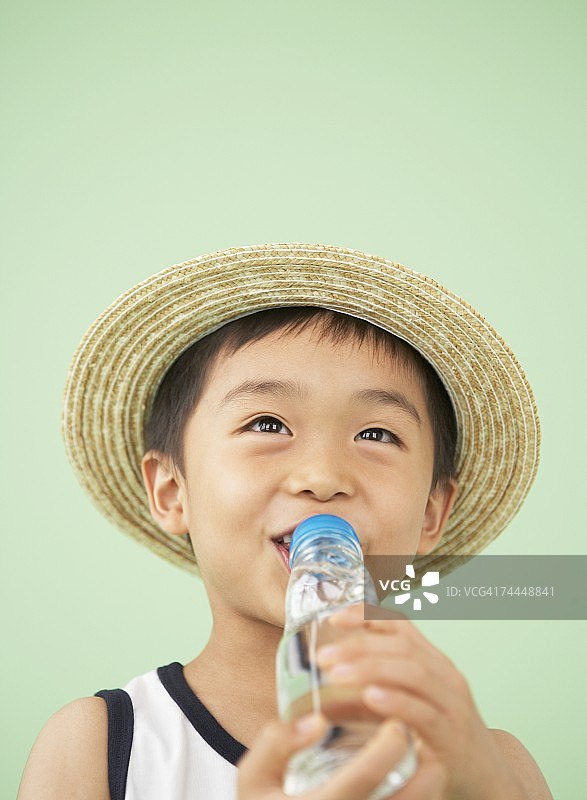 戴帽子喝果汁的日本男孩图片素材