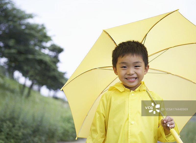 穿着黄色雨衣、撑着伞的日本男孩图片素材