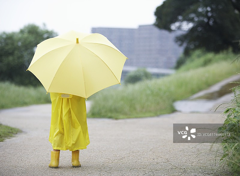 穿着黄色雨衣、撑着伞的日本男孩图片素材