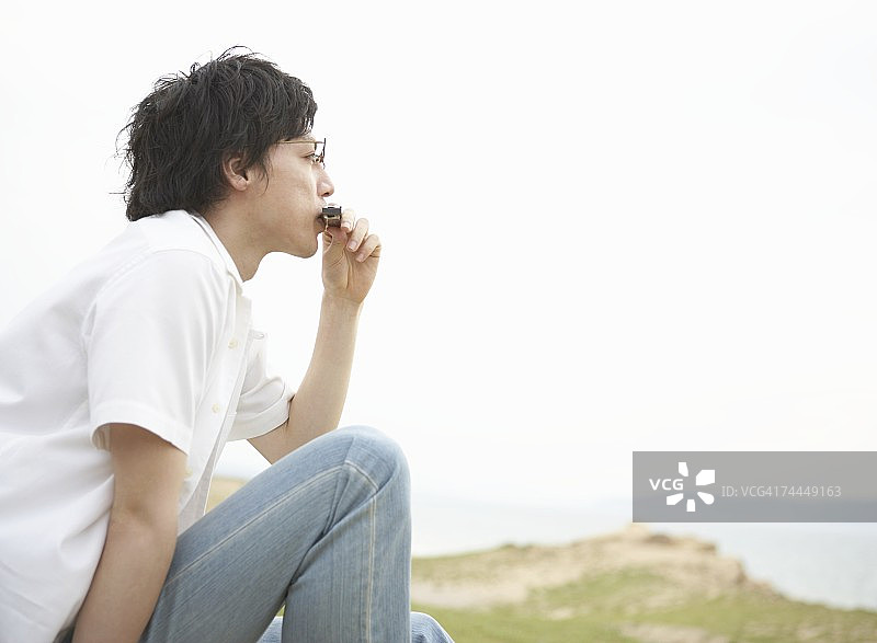 坐在沙滩上吹口琴的男人图片素材