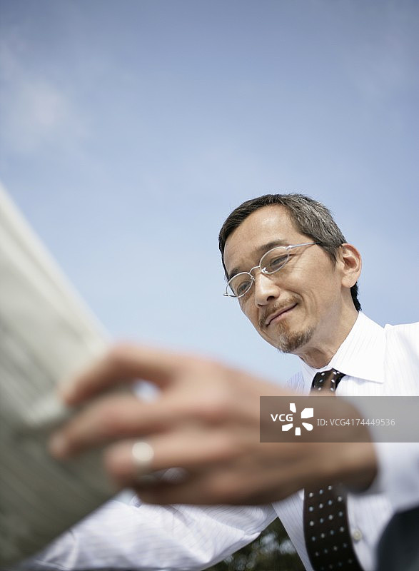 在海滩上阅读报纸的日本成年男子图片素材