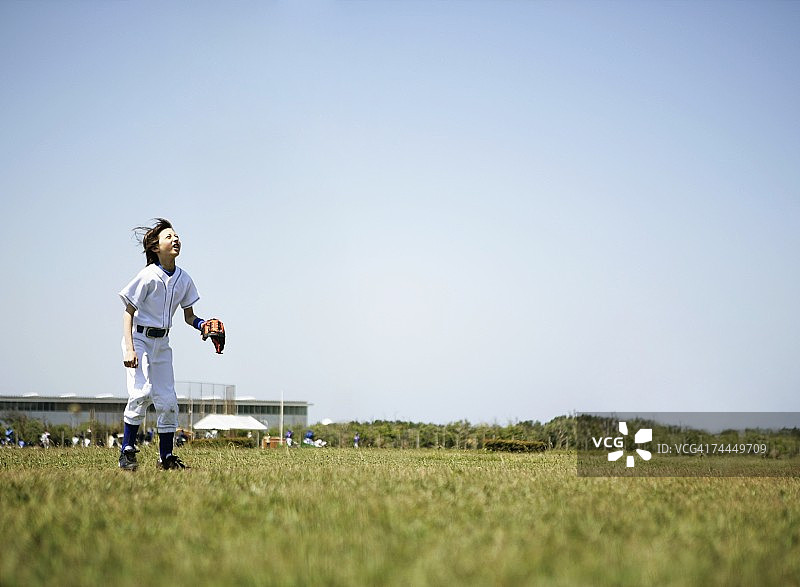 穿着棒球服站在草地上的美国男孩图片素材