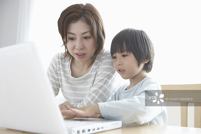 和儿子一起看笔记本电脑的日本女人图片素材
