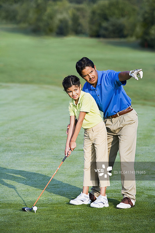 西班牙裔父亲帮助女儿打高尔夫球图片素材