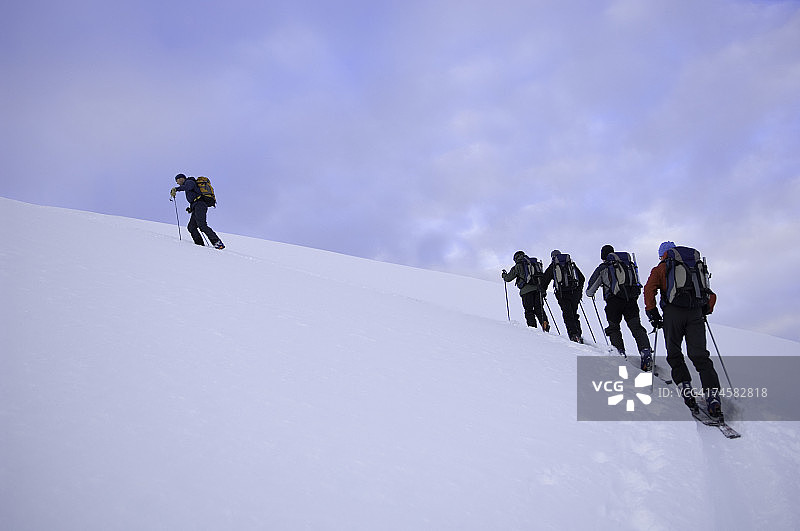 一群人在雪地攀登，一人领先，低角度后视图图片素材