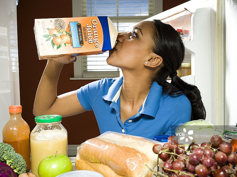 女人在冰箱里喝橙汁，周围是健康食品图片素材
