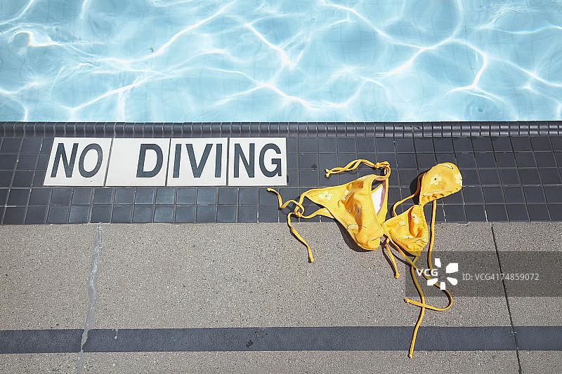 泳池旁丢弃的比基尼和禁止跳水标志，俯视图图片素材