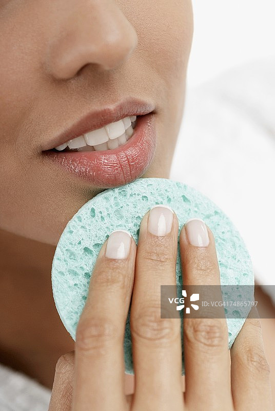年轻女子用海绵擦下巴特写图片素材