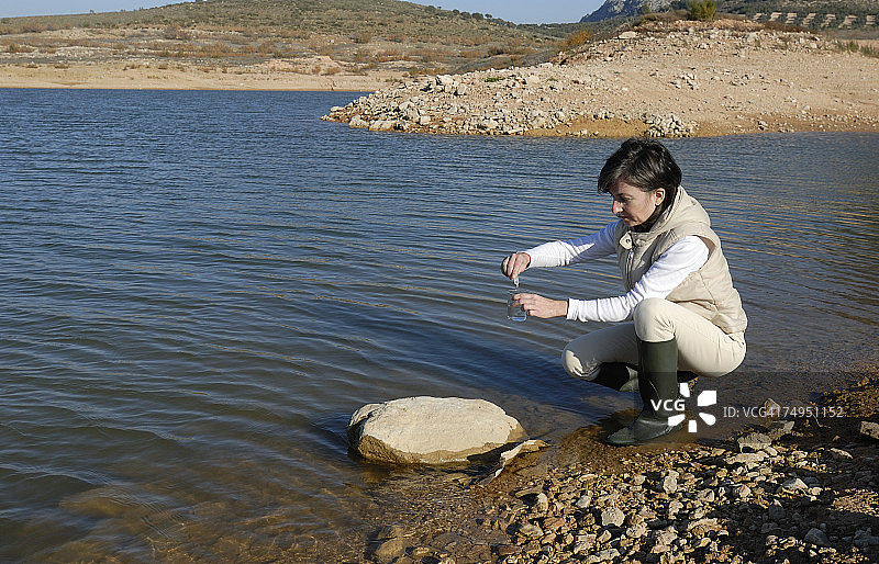 女科学家从湖中取水样（侧视图）图片素材