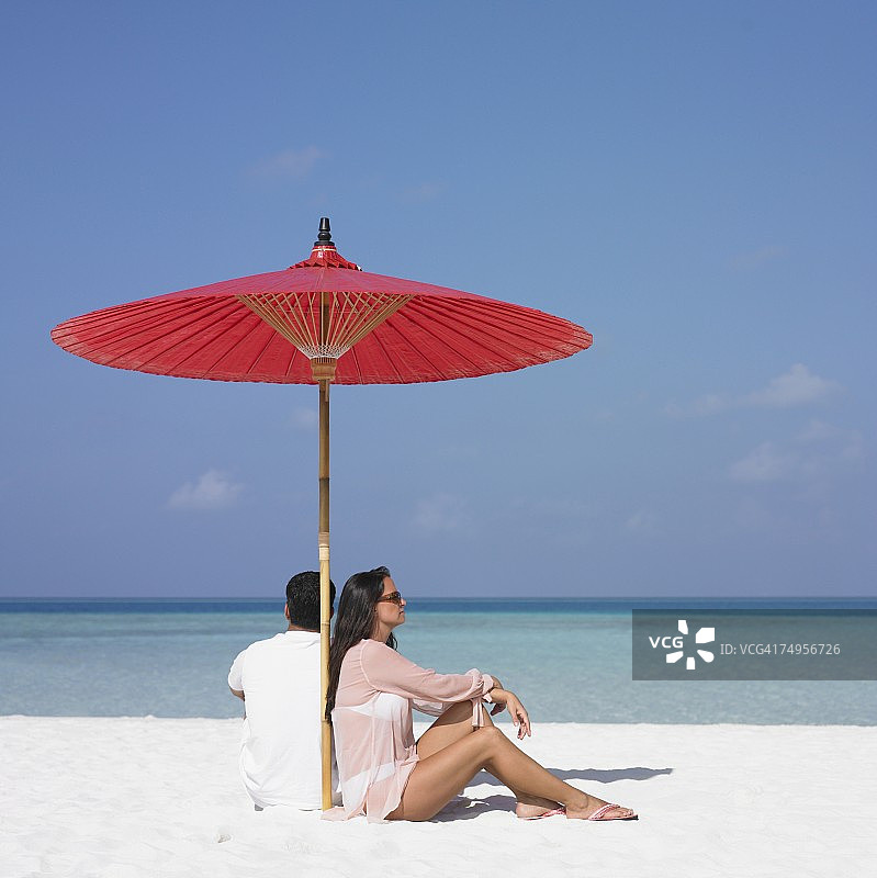一对西班牙裔夫妇在海滩的伞下图片素材