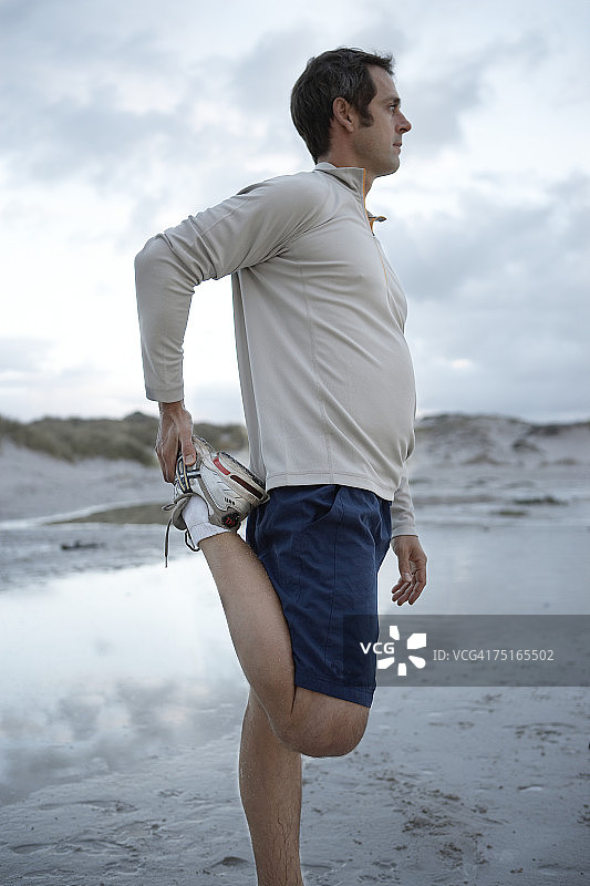 在海滩上伸腿的男人（侧面视角）图片素材