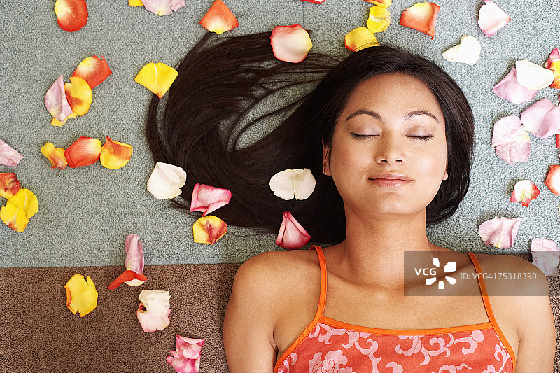 俯视：年轻女子躺在花瓣中图片素材