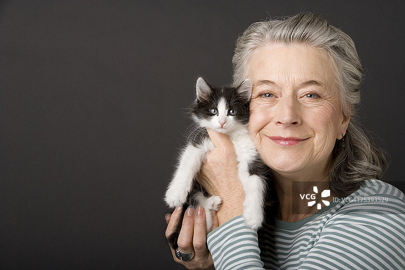 在影棚里抱着小猫的年长女人肖像图片素材