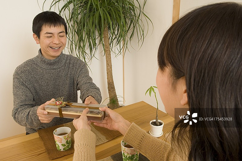 年轻女子赠送情人节礼物给年轻男子图片素材