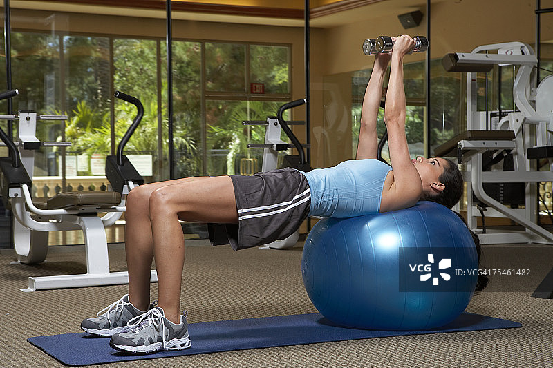 在健身球上用哑铃锻炼的女人图片素材