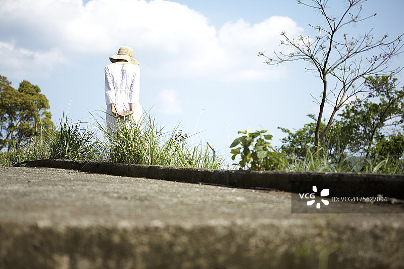 戴太阳帽和夏装的女人在草地和树林中行走图片素材