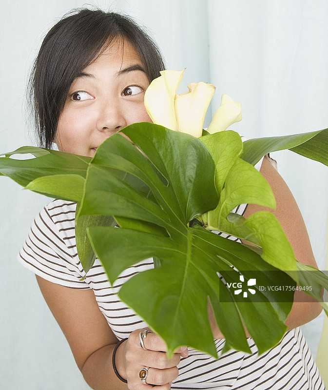 女人从树叶和鲜花上方向外窥视图片素材