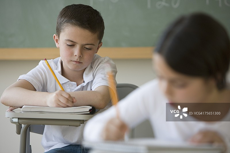 男孩在教室课桌前写字图片素材