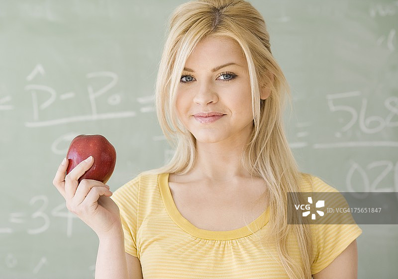 女人在黑板前拿着苹果图片素材