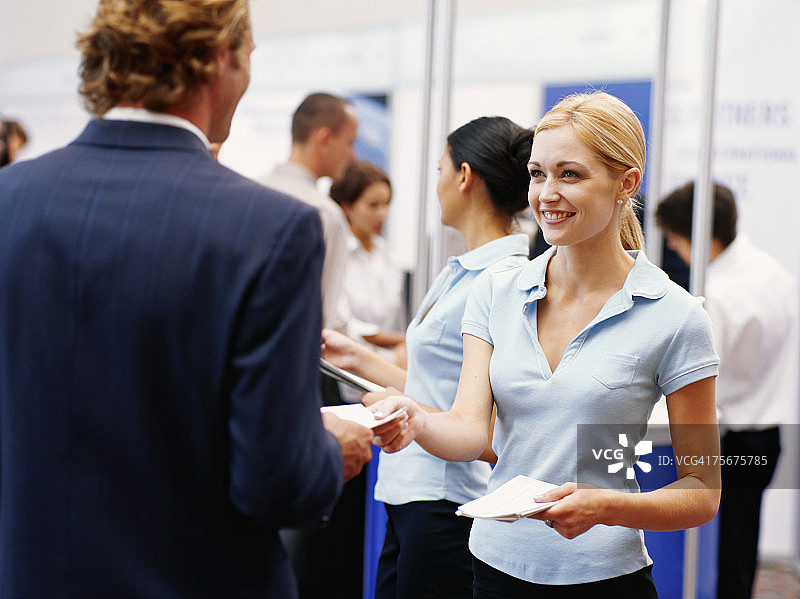 在展览会上向商人分发宣传册的销售主管图片素材