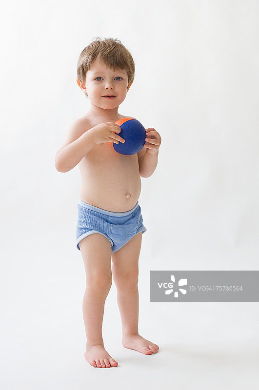 拿着球站在白色背景前的男孩（2-3岁）肖像图片素材