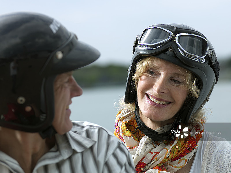 一对中年夫妇戴着头盔在户外，深情对视，笑容满面图片素材