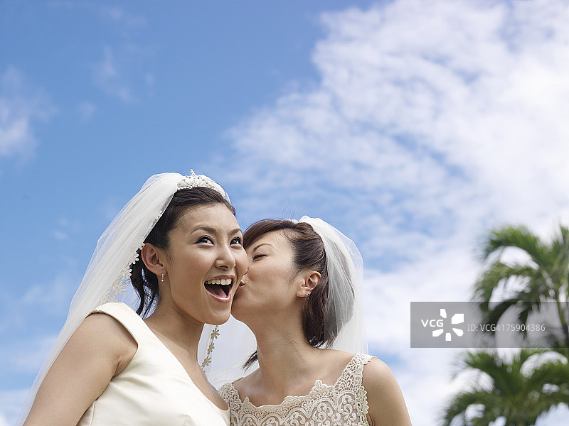 蓝天下，新娘亲吻另一位新娘图片素材