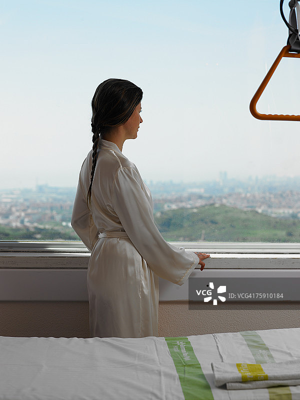 穿着浴袍的女人在看窗外图片素材
