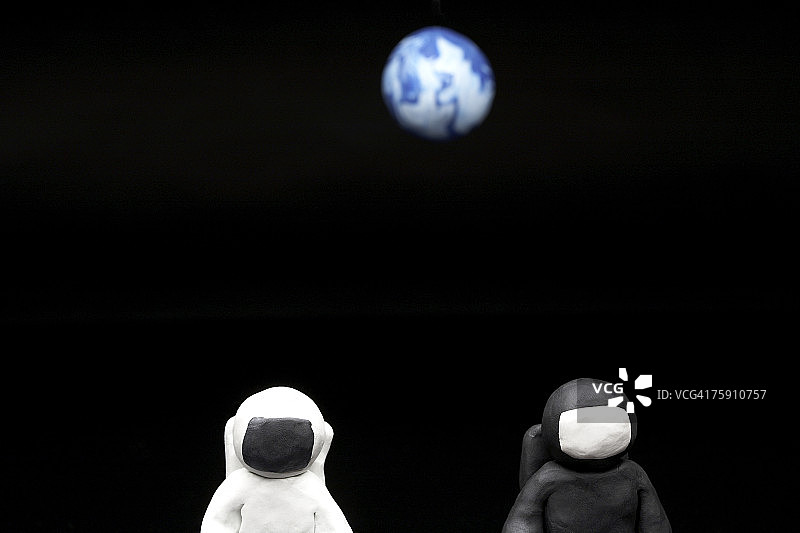 黑色背景下，黏土宇航员与地球图片素材
