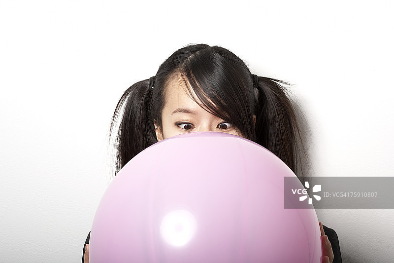 年轻女人手持粉色气球，对眼特写图片素材