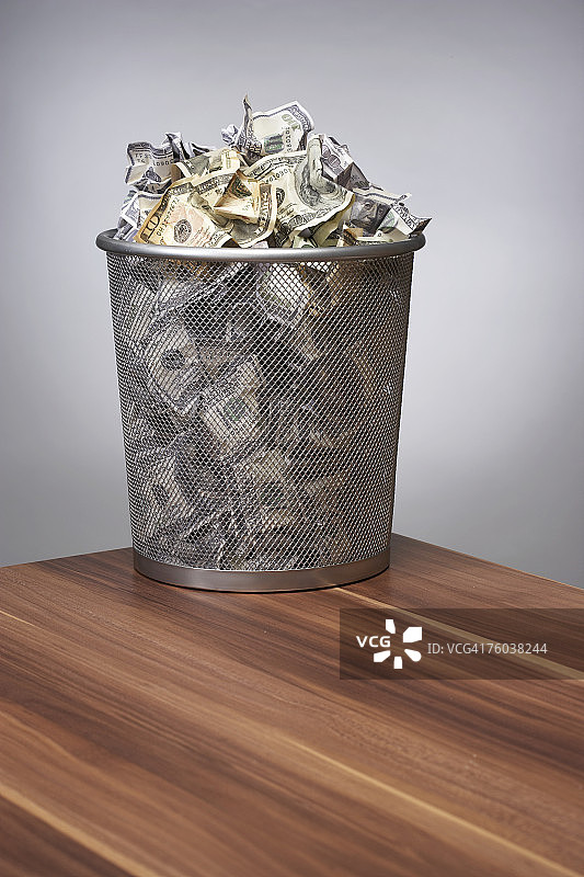 办公桌上装满美元的废纸篓图片素材