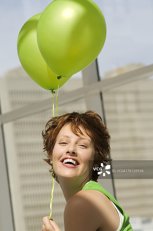 年轻女子拿着绿色气球的肖像图片素材