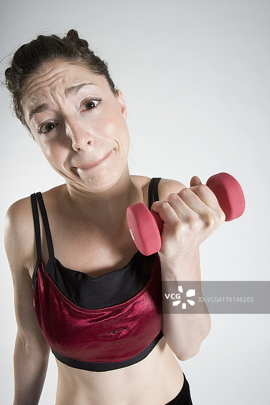 使用哑铃的年轻女人肖像图片素材