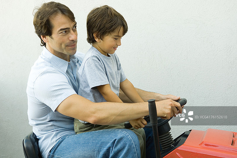 父子俩一起骑着割草机图片素材