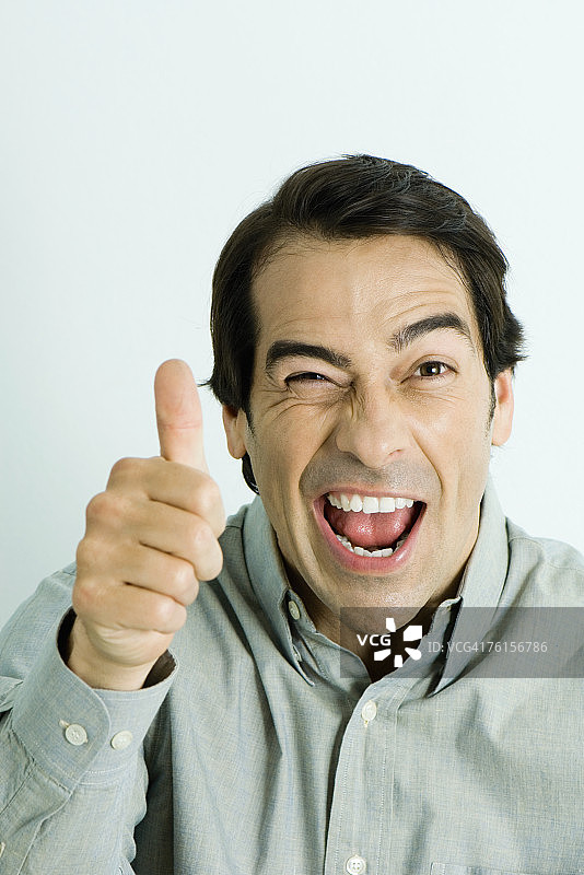 男人竖起大拇指，眨眼，肖像图片素材