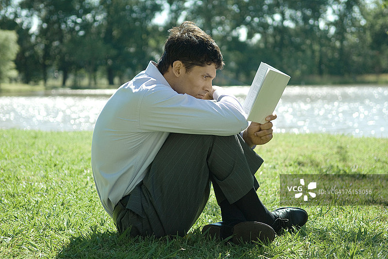 坐在草地上阅读的商人图片素材