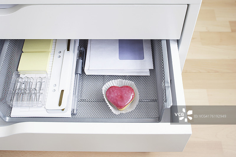 打开的办公桌抽屉，里面有心形蛋糕图片素材
